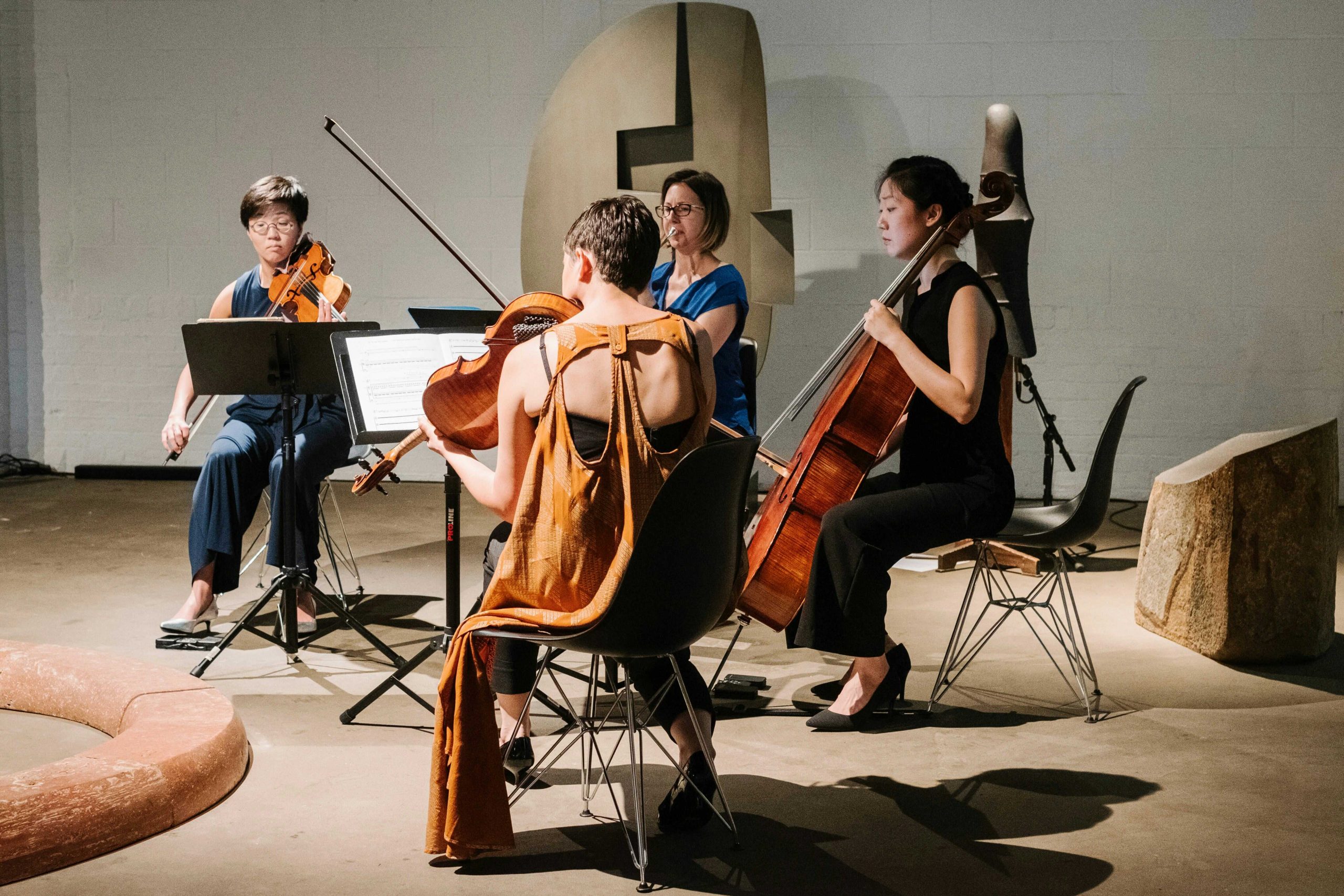 String trio and horn player performing in museum with contemporary sculpture